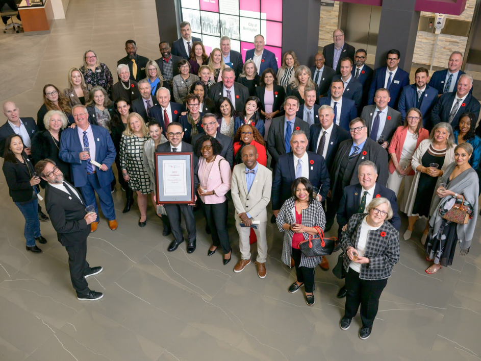 DeGroote College's faculty, alumni, staff, and dean gathered together in a lobby for a group photo.