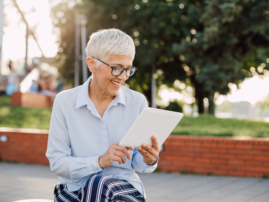 A senior professional smiling as they scroll on a tablet.