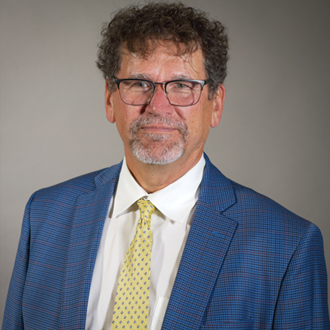 Portrait of Frank Gerencser, a smiling man wearing a blue suit.
